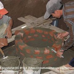 Image shows workmen building a fixed dome biogas digester.