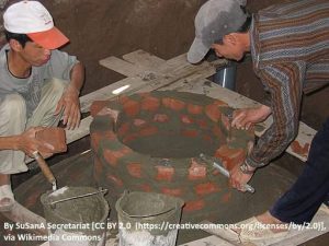 Image shows workmen building a fixed dome biogas digester.