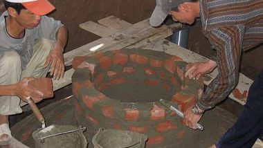 Image shows workmen building a fixed dome biogas digester.